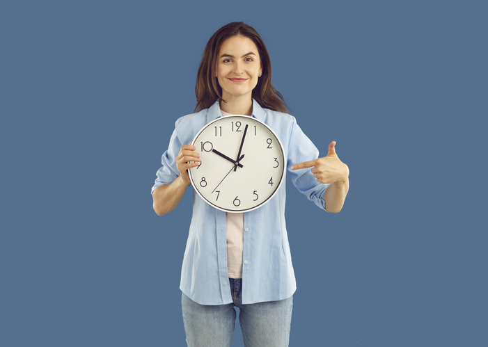 Portrait of beautiful happy young brunette holding round wall clock.