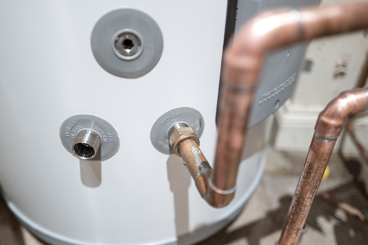 Shallow focus of inlet and outlet flow connections on a newly installed hot water tank in a private home.